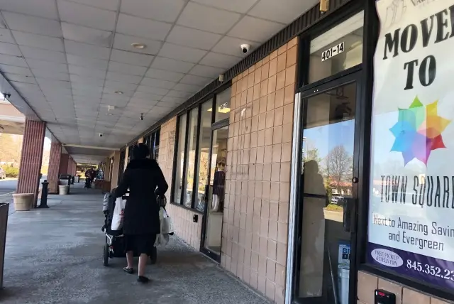A woman pushes a stroller outside the Designer Spot, one of the establishments in Monsey where Rockland County officials say people were exposed to measles.